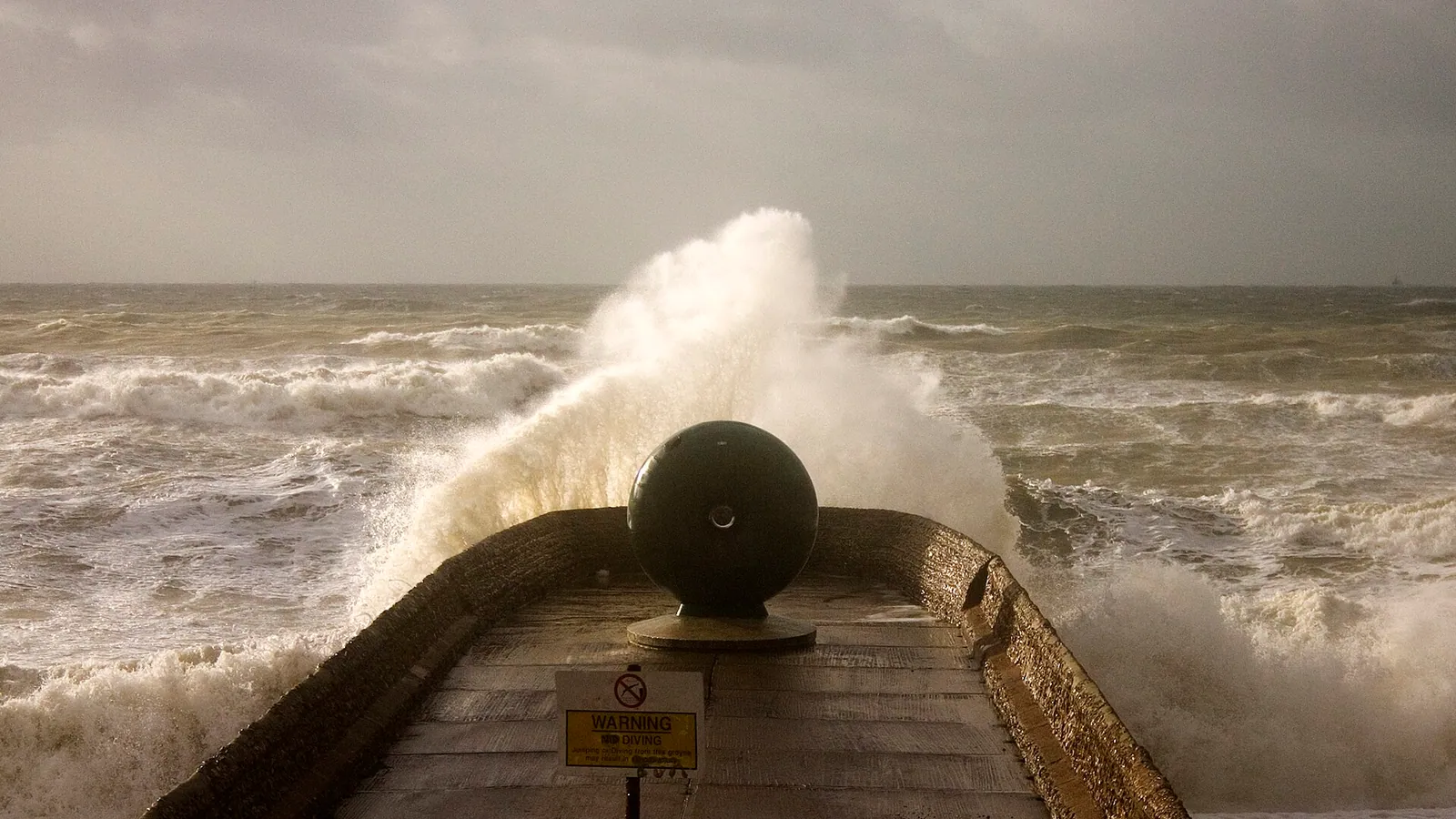 Storm waves breaking over a sea wall in a strong onshore wind