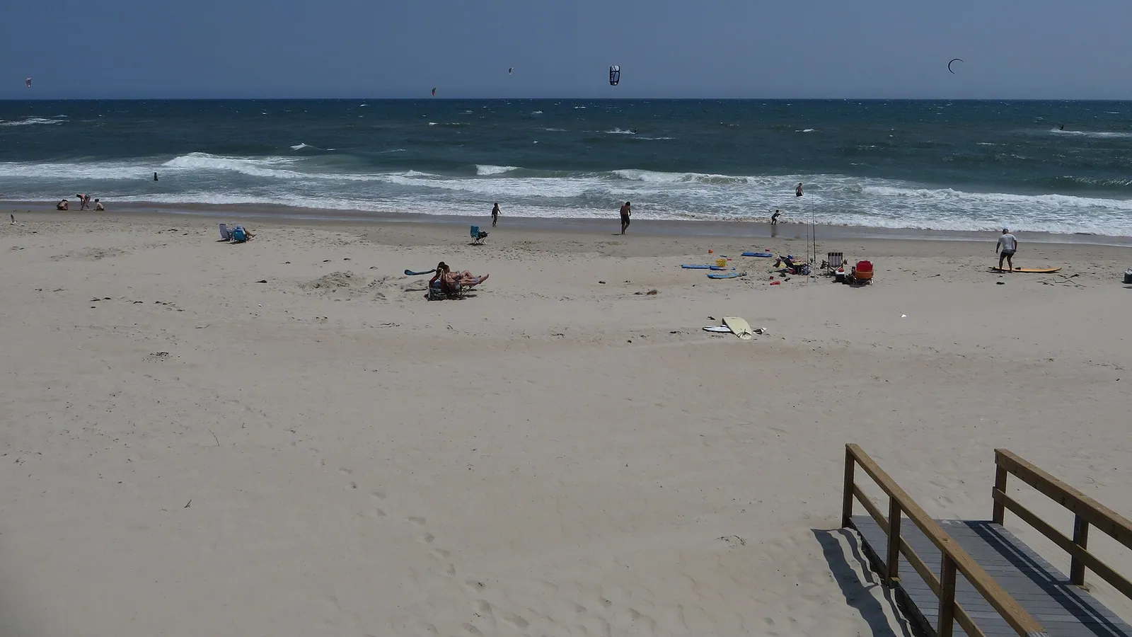 A breezy ocean kite beach with several kitesurfers out on the water