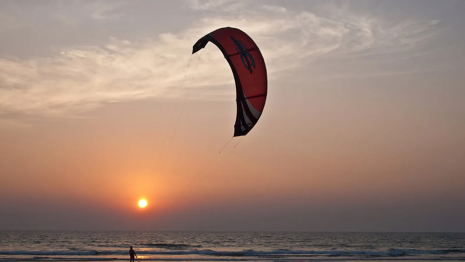 Kitesurfers riding a bright turquoise bay under a clear sky