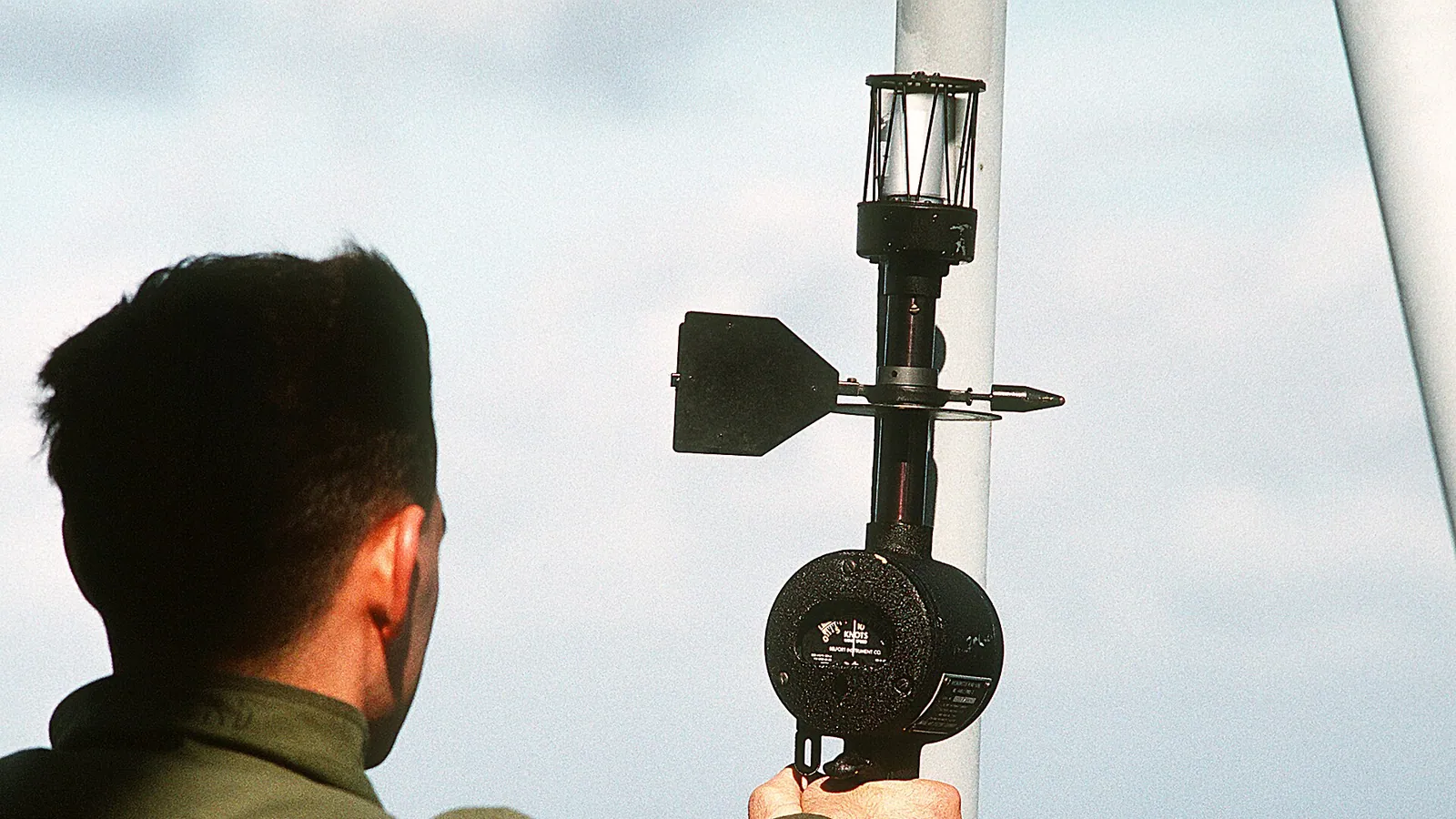 An anemometer's spinning cups against a blue sky, measuring wind speed in metres per second