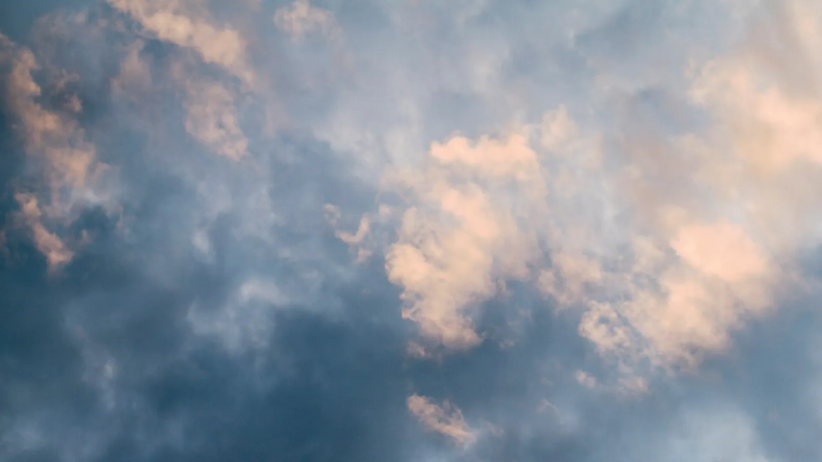 A sky full of clouds lit by warm evening light